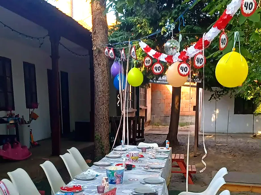 Ünnepi hosszú asztal a Marcsi Varázs Lak kertjében, lufikkal és füzérekkel díszítve egy születésnapra